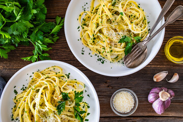 Pasta with garlic, parsley and parmesan cheese on wooden table. Spaghetti aglio olio on wooden background