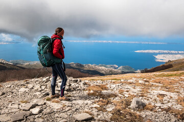 Young woman standing on top of a mountain overlooking the sea. Croatia, Velebit mountain range