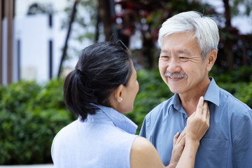 Naklejka premium Happy smiling Asian senior couple in urban park with good quality of life, staying together, taking care of each other with positive expressions after retirement, real human, real people model
