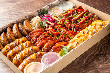 A generously arranged barbecue platter featuring ribs, chicken wings, sausages, corn, and dipping sauces, highlighting a delectable assortment for a festive occasion.