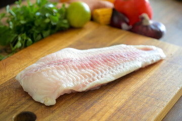Uncooked Fish on wooden kitchen board with vegetables citrus for seviche recipe