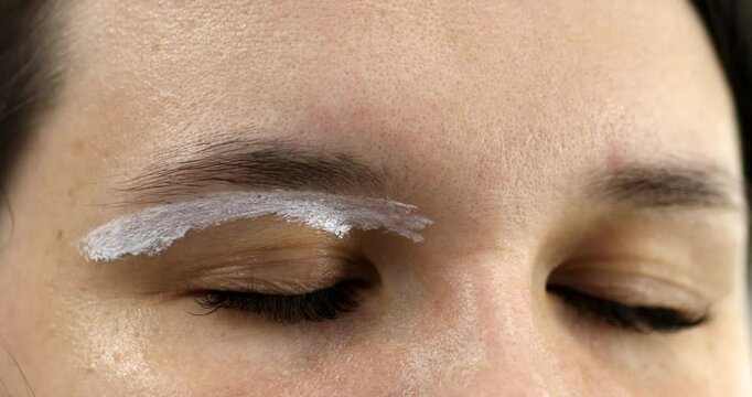 Brow master draws white markup on the eyebrows of a model