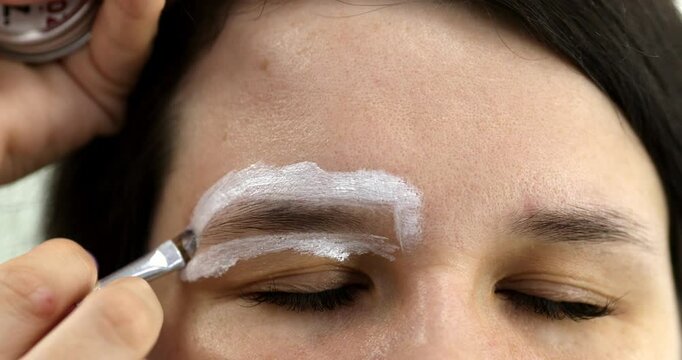 Brow master draws white markup on the eyebrows of a model