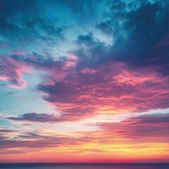 Obraz premium Stunning sunset sky over ocean Vibrant colors of orange, pink, and purple clouds blend with a deep blue sky above a calm ocean horizon