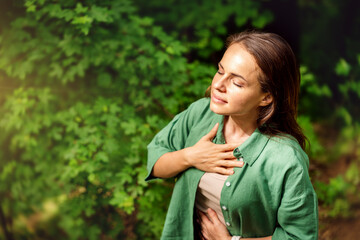high angle view of young adult woman practising breathing exercise in the forest in summer.