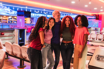 Group of young, cheerful, multi ethnic friends laughing and enjoying each other's company while having fun at a vibrant bowling alley