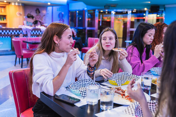 Group of female friends enjoying a meal together at a bowling alley restaurant, celebrating friendship and leisure time