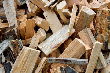 Stack of split firewood logs with rough textures and natural patterns, prepared for heating or campfire use, captured in daylight.