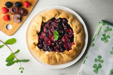 Galette tart with red berries, cherries, raspberries and blackberries. Top view table with christmas decoration.