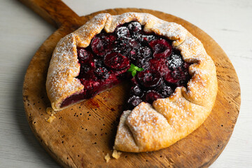 Galette tart with red berries, cherries, raspberries and blackberries. Top view table with christmas decoration.