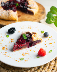 Galette tart with red berries, cherries, raspberries and blackberries. Top view table with christmas decoration.