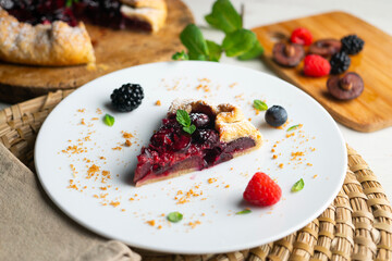 Galette tart with red berries, cherries, raspberries and blackberries. Top view table with christmas decoration.