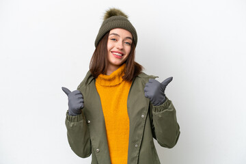 Young Ukrainian woman wearing winter jacket isolated on white background with thumbs up gesture and...