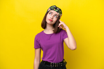 Young Ukrainian woman isolated on yellow background making the gesture of madness putting finger on the head