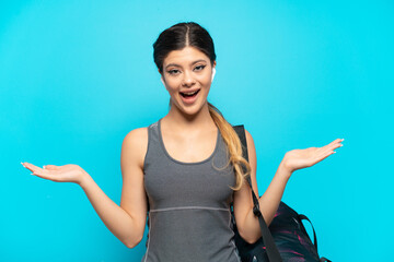 Young sport Russian girl with sport bag isolated on blue background with shocked facial expression