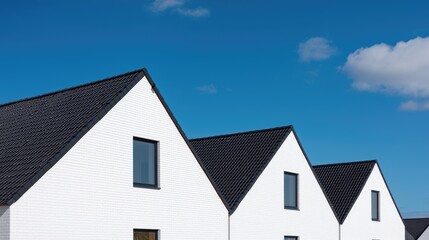 Modern row houses with dark roofs against a clear blue sky