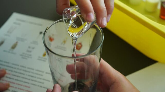 Person pouring substance into a glass as an experiment