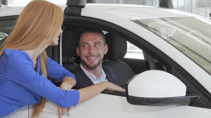 Charming man engaging with his wife while selecting a new car at the dealership