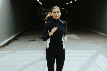 Energetic woman jogging in a tunnel during the early morning hours