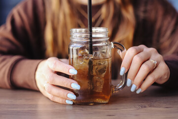 Long island iced tea in glass. Woman holding cold drink. Fresh beverage with ice cubes. Summer refreshment.Refreshing cold tea. Chilling with drink. Casual lifestyle. Healthy summer drink.
