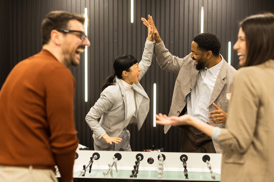 Joyful celebration among friends during a foosball game in a stylish indoor setting