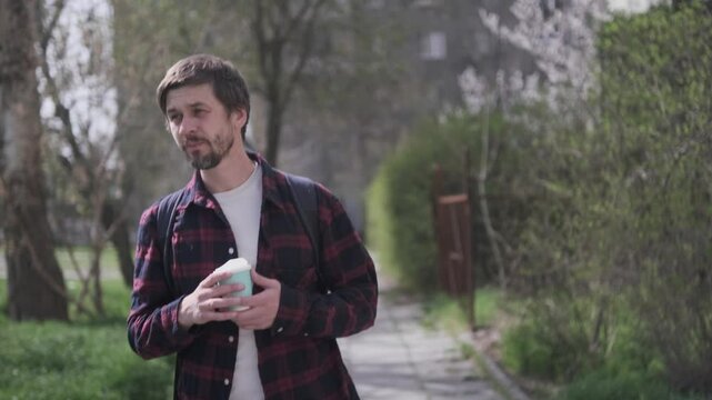 Cheerful man holding coffee cup outdoors smiling on sunny street