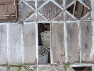 Weathered glass panes reveal hidden containers in an abandoned structure with peeling paint and natural textures