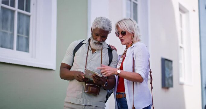 Mature couple, outdoor and map for directions to navigate city as tourist on holiday, break and relax. Interracial relationship and people with pointing for traveling, tour and vacation on location