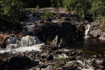 Norwegian mountain river with waterfalls where rapid water flows, creating white foam.