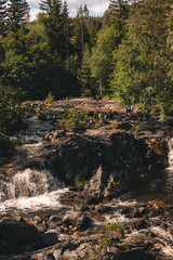 Norwegian mountain river with waterfalls where rapid water flows, creating white foam.