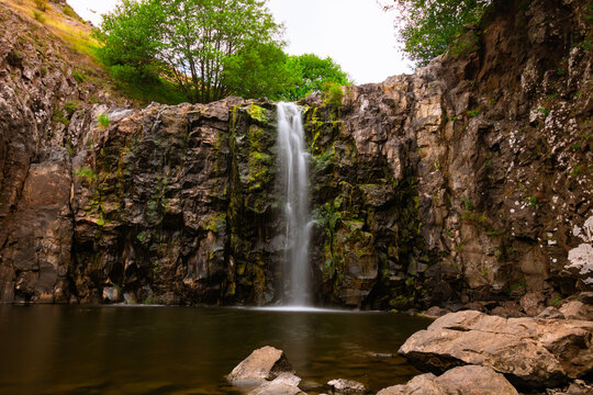 Flowing creek water over the rocks of a waterfall in the summer.