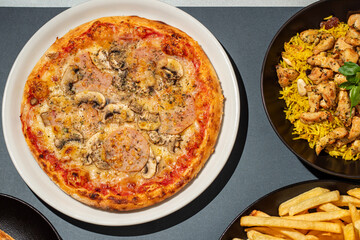 Pizza, chicken sandwich, French fries, rice and other food served on a table, top view