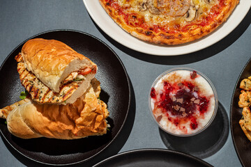 Pizza, chicken sandwich, French fries, rice and other food served on a table, top view
