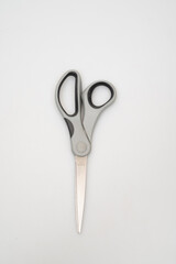 Close-up of a pair of grey and silver scissors on a white surface close-up photo macro view