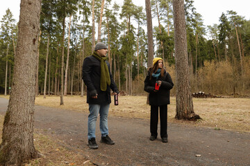 forest tourism showing people in layered outerwear, holding travel mugs and enjoying companionship in a serene recreational nature park.