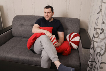 Man Enjoying Popcorn While Watching TV at Home with Relaxing Atmosphere