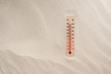 Wooden celsius and fahrenheit scale thermometer in the sand. Ambient temperature plus 50 degrees. Hot summer day