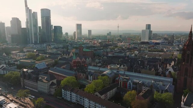 Aerial view of Frankfurt, Germany, showing the Main River, Eiserner Steg bridge, modern skyscrapers, historic buildings, and a moving boat.