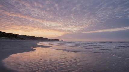 Coastal landscape at sunrise with dunes, beach, ocean, and hills