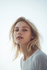 Fototapeta premium Blonde woman gazes with windswept hair. Simplicity and natural beauty shining, captured in this portrait.