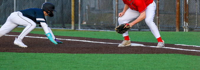 Baseball player diving back to first base during a pickoff play in a baseball game