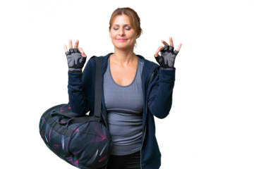 Middle-aged sport woman with sport bag over isolated background in zen pose