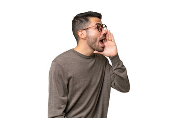 Young handsome caucasian man over isolated background shouting with mouth wide open to the side