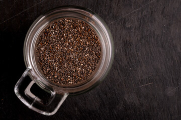 Chia seeds in glass jar on rustic dark background, healthy organic superfood