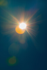 Obraz premium Bright sunlight with colorful lens flare against clear blue sky