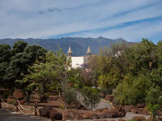 Natural landscape with trees, volcanic rocks and a view of a historic church among mountains under...
