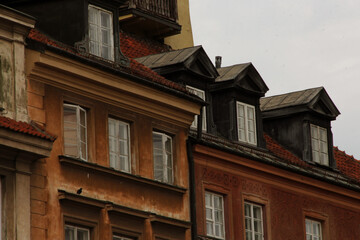 Obraz premium Historic residential architecture with stucco facades, dormer windows, red tile roofs and weathered textures in warm brown and orange colors, captured in overcast light for a vintage atmosphere