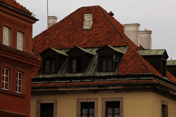 Traditional red tiled rooftop with vintage dormer windows and white chimneys on a historic building...
