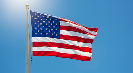 Fototapeta premium Brightly waving American flag with stars and stripes against a clear blue sky, concept for patriotism, national pride and USA celebration
