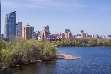 Fototapeta premium Beautiful view of Obolonskaya embankment. View from the bridge to the city embankment and the Dnieper river in Kyiv in spring. Beautiful landscape of the city of Kyiv, Ukraine